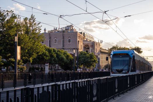 A modern tram travels through the historic streets of Istanbul at sunset with a historic building in the background.