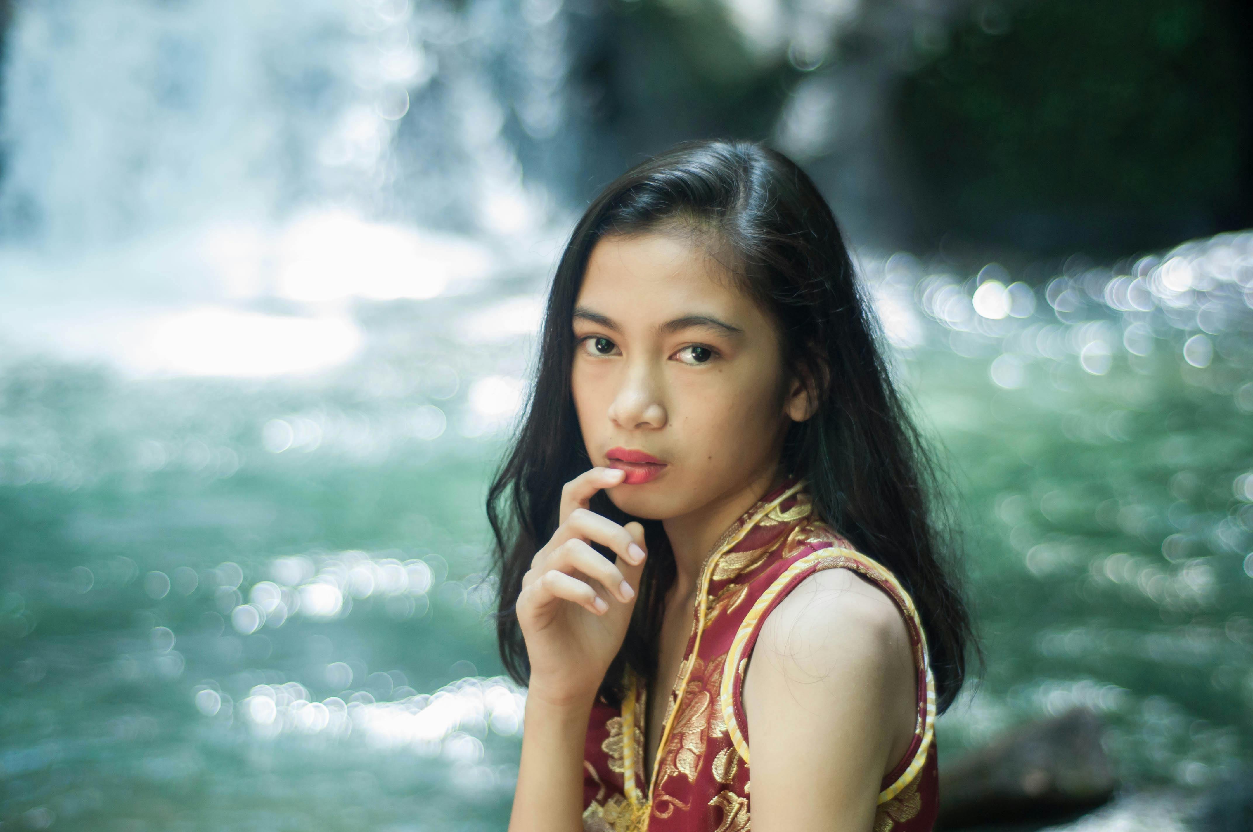 一位优雅的女性肖像，静置于被大自然环绕的瀑布旁