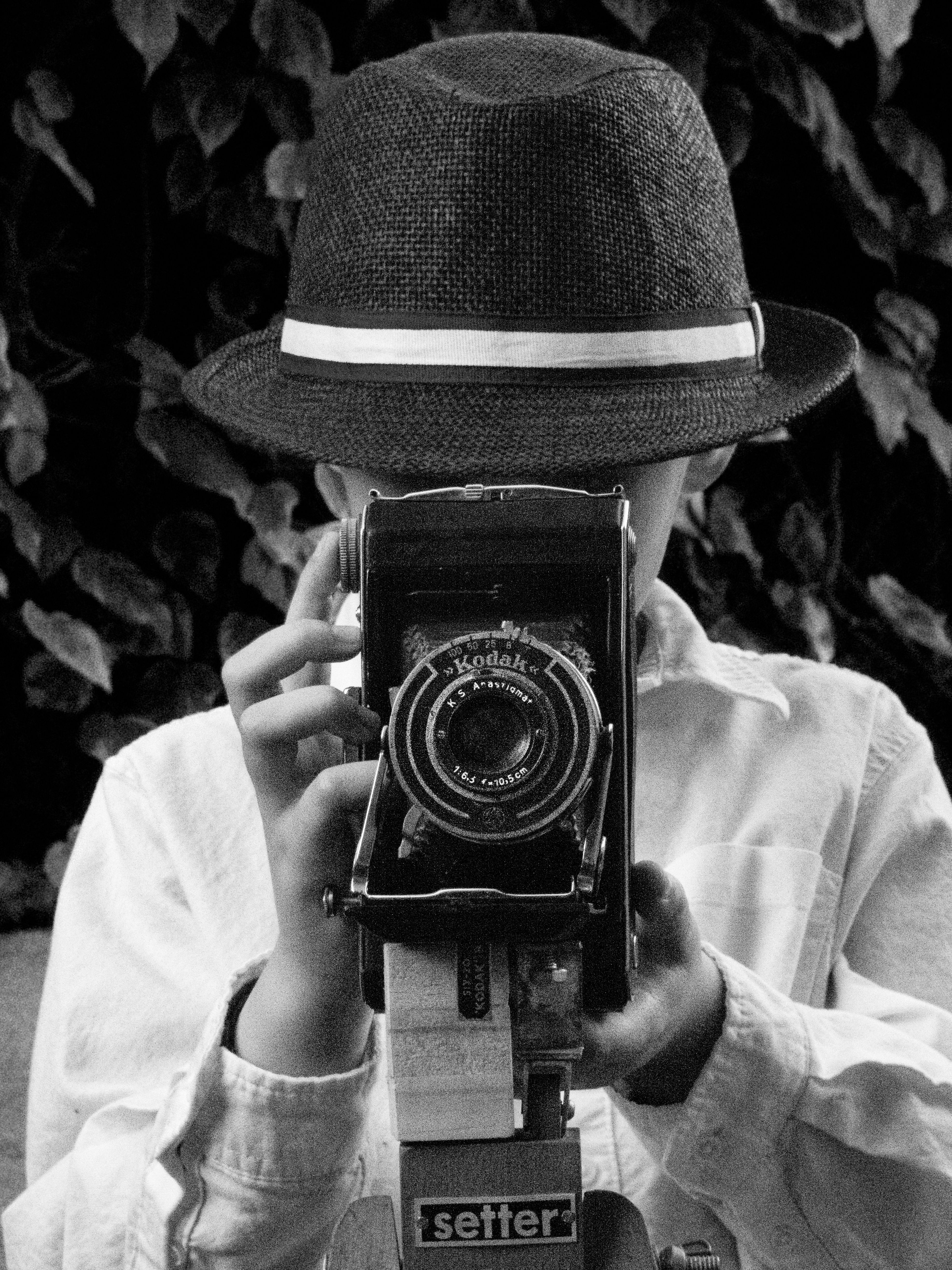 Child in a hat holding a vintage Kodak camera, evoking nostalgia.