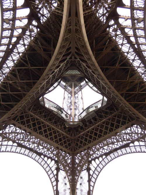 Free Detailed view of the intricate ironwork underneath the Eiffel Tower in Paris. Stock Photo