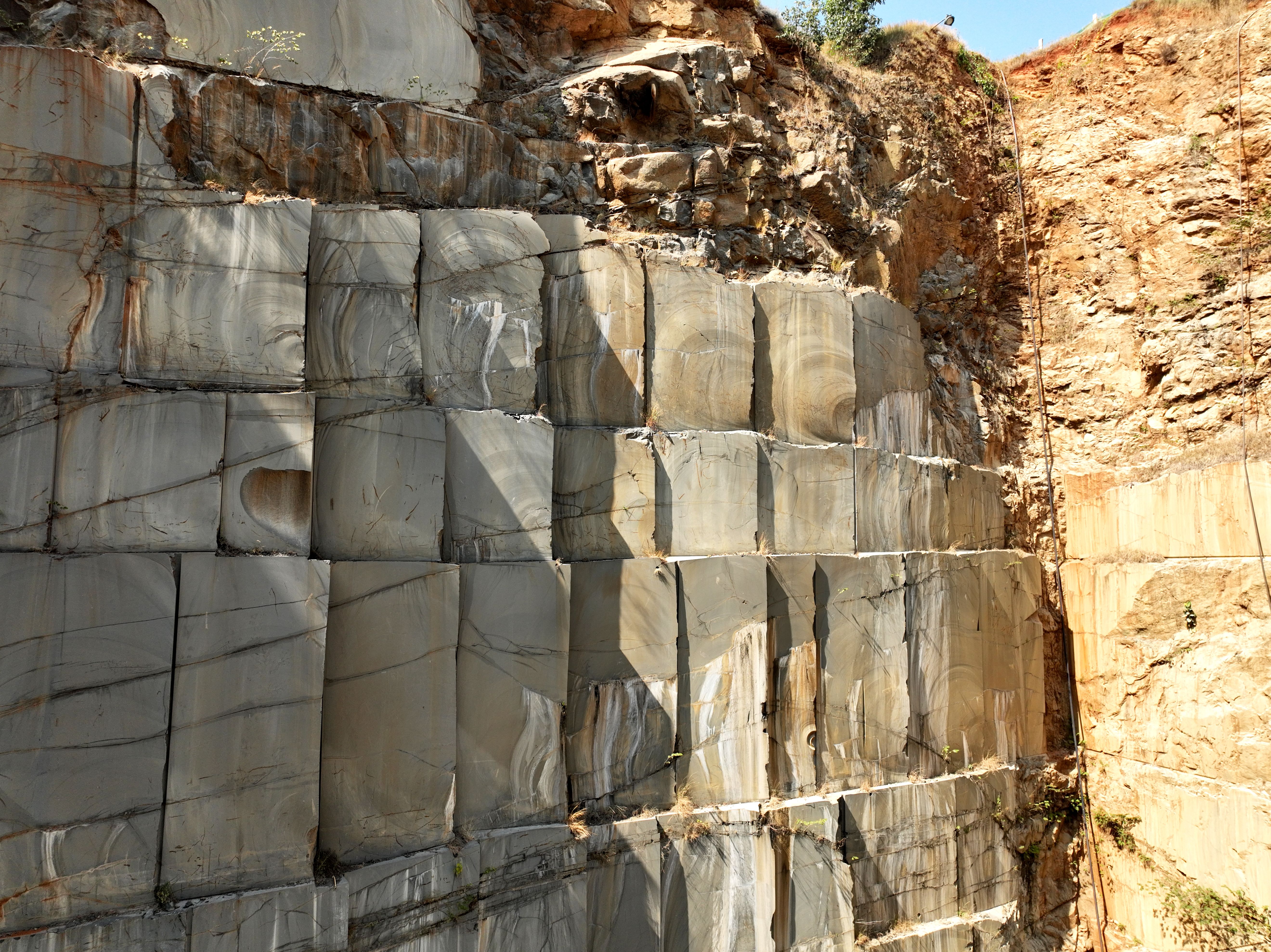 Granite quarry wall illuminated by sunlight — West Azerbaijan stone quarries for export to Turkey and Iraq