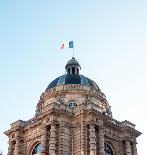 Free Capture of a classical dome in Paris with the French flag atop, showcasing architectural elegance. Stock Photo
