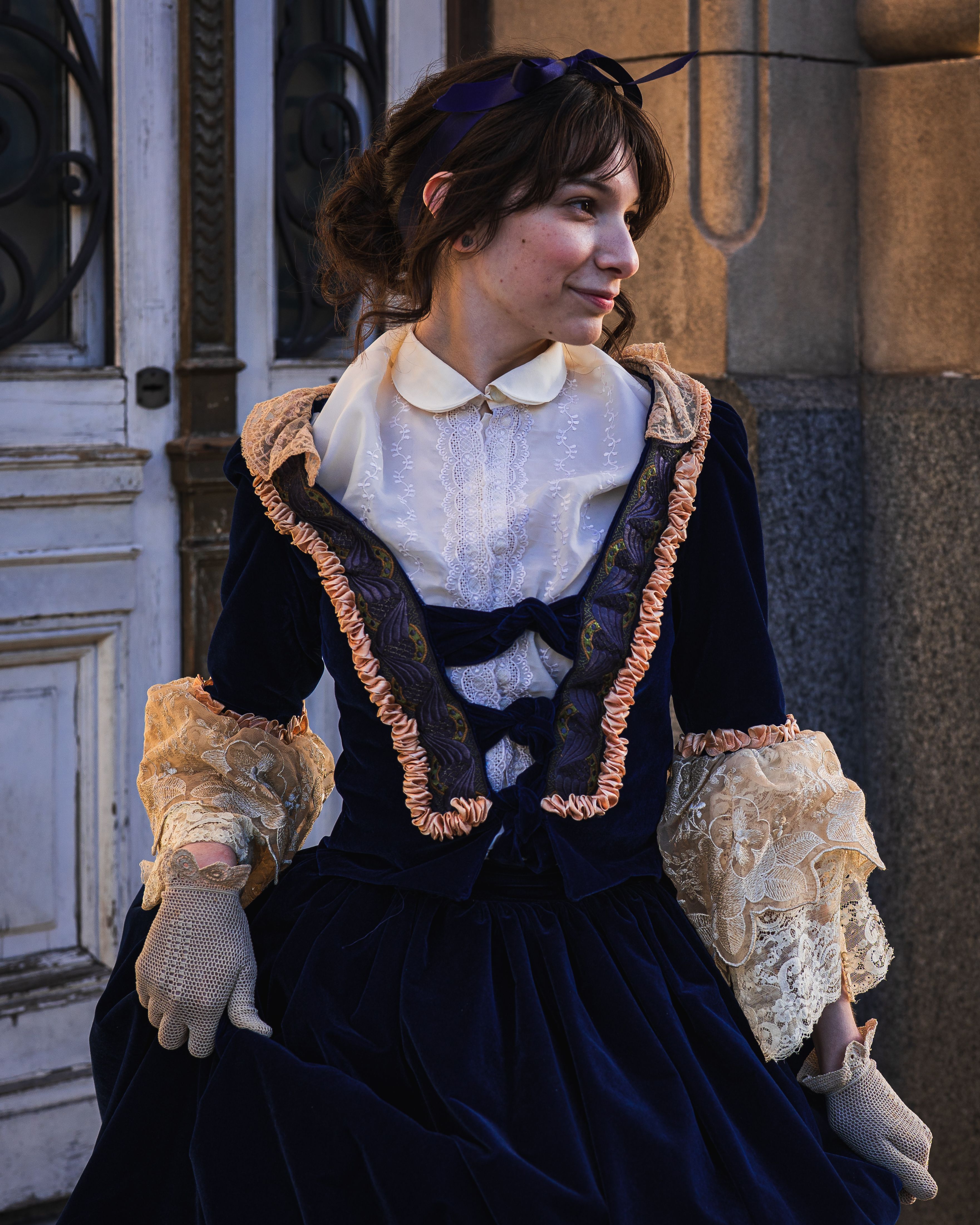 Woman wearing vintage Victorian style dress outdoors, looking sideways.