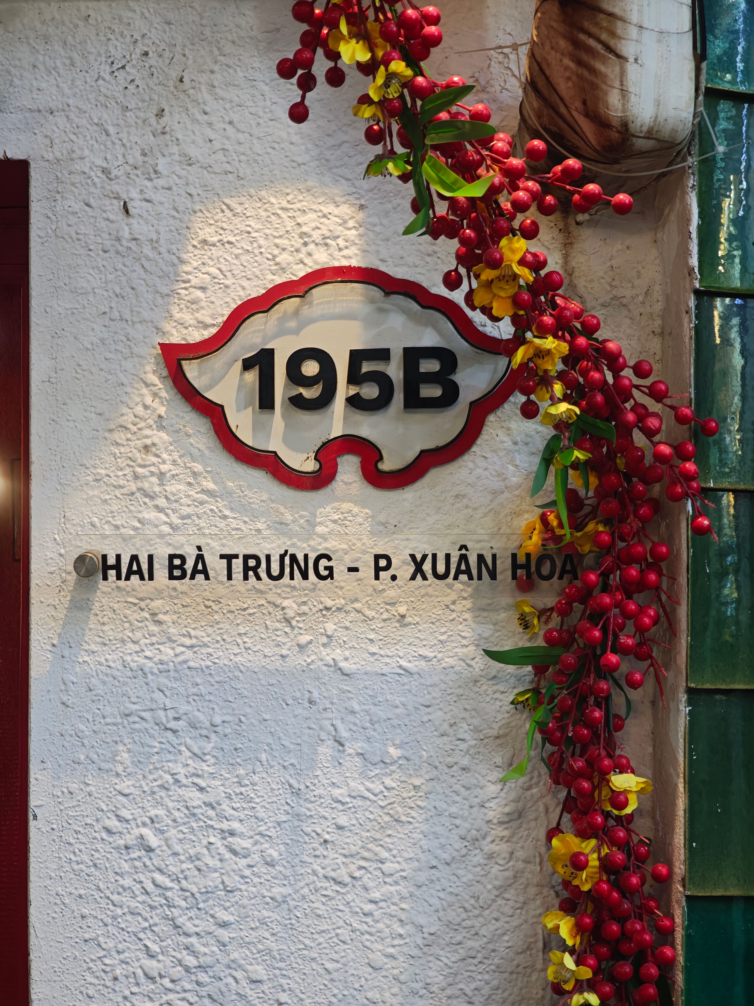 Colorful wall address sign 195B with vibrant foliage and flowers on a stucco wall.