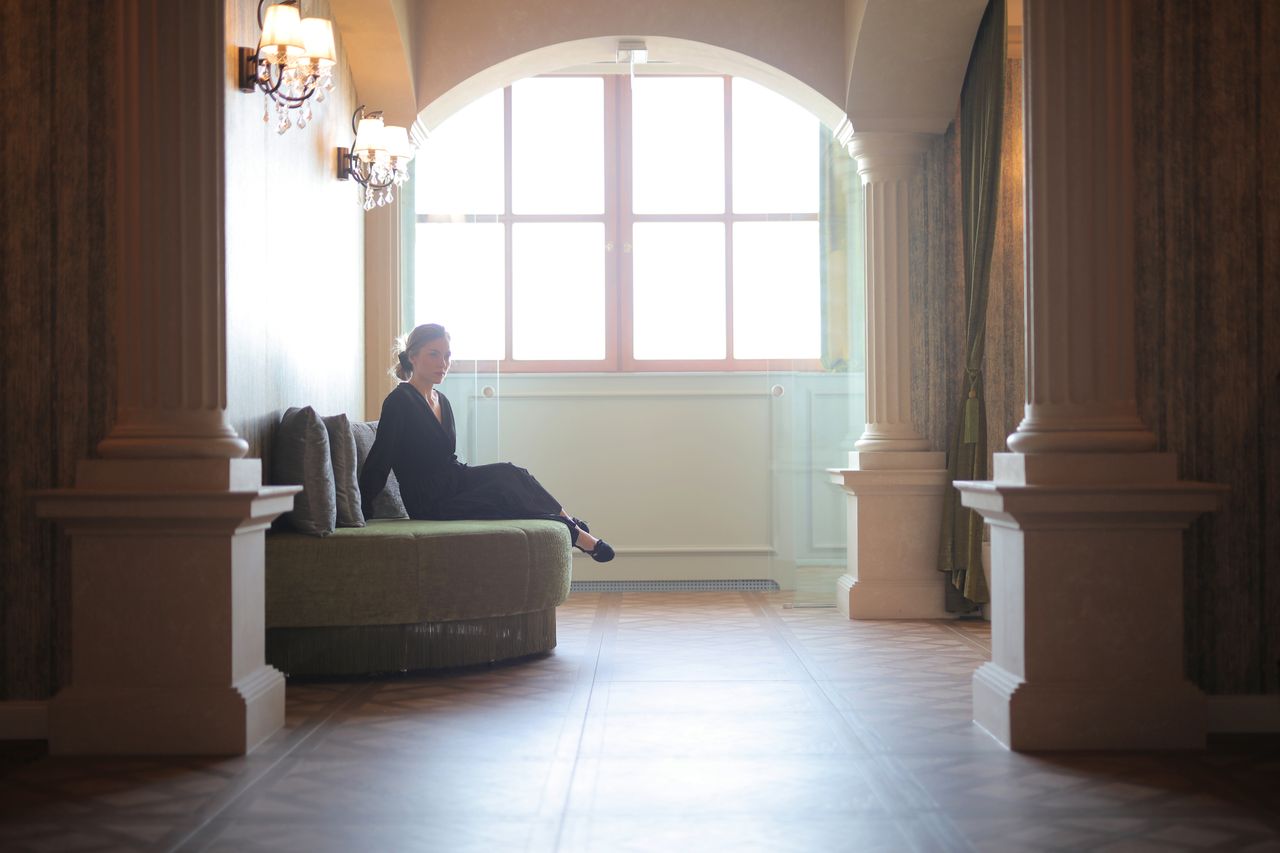 a woman in a black dress sits elegantly in a classic lobby framed by a