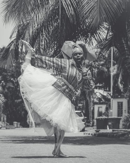Free Black and white photo of a dancer in elaborate traditional costume posing gracefully outdoors. Stock Photo
