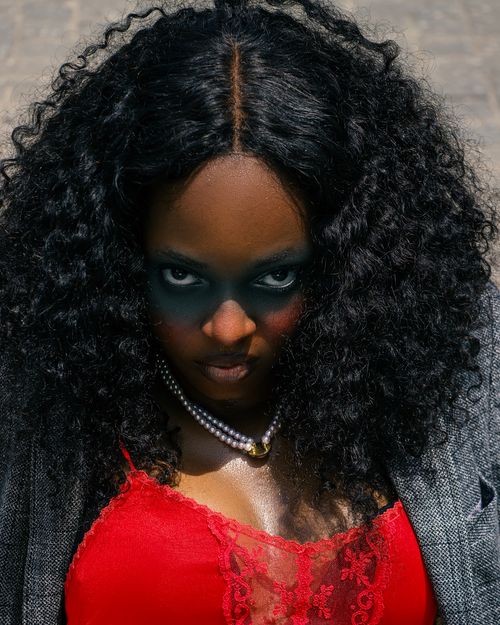 Free Close-up portrait of a woman with bold makeup and curly hair in outdoor setting. Stock Photo