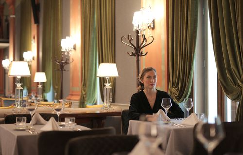 Free Woman sitting alone in a luxurious restaurant, surrounded by elegant decor and dim lighting. Stock Photo