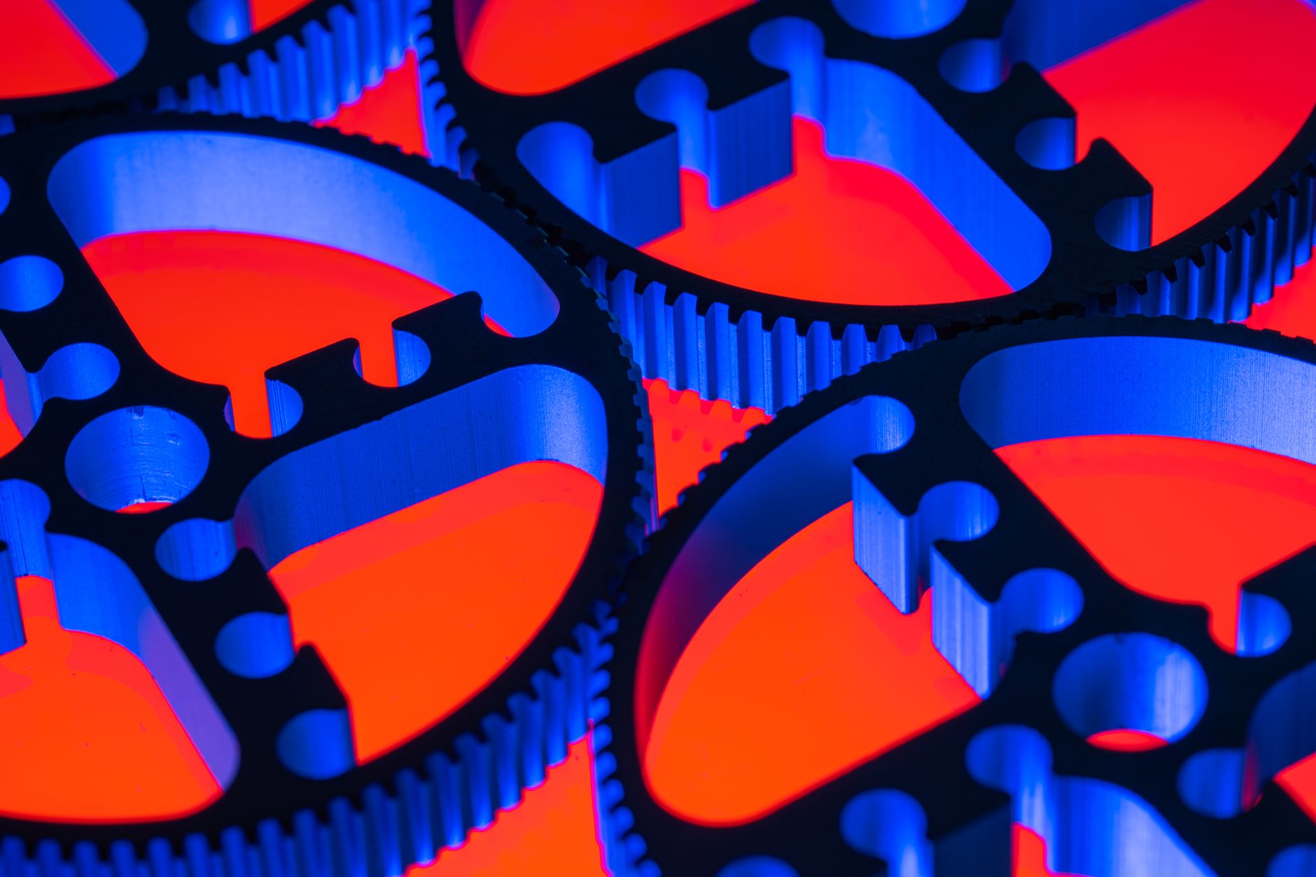 Colorful macro image of blue metallic gears against a red background, highlighting engineering precision.