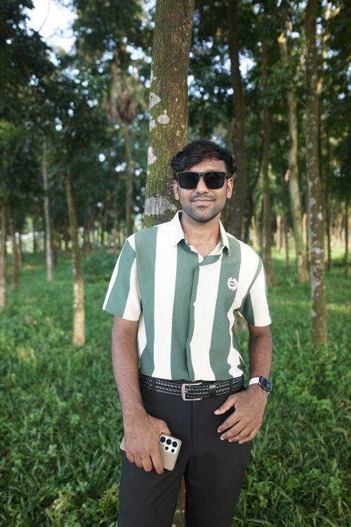 Free A man stands against a tree in a lush forest, wearing sunglasses and holding a smartphone. Stock Photo