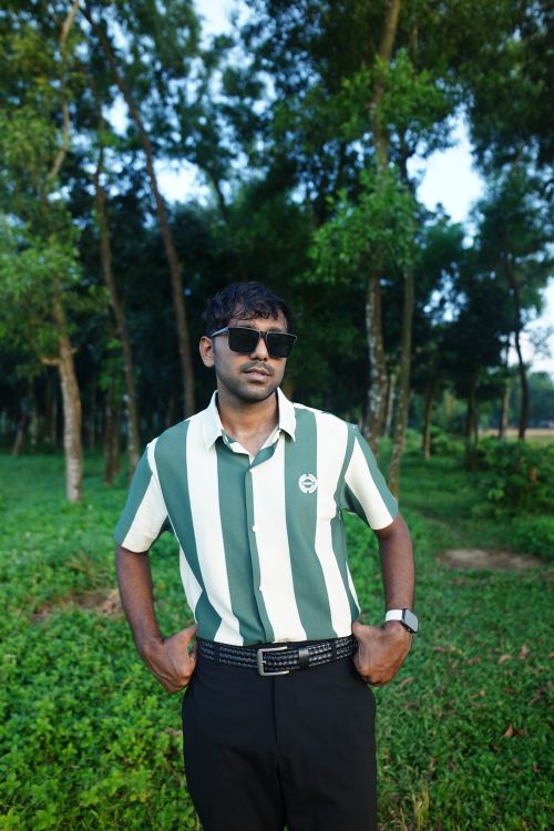 Free Stylish man in sunglasses standing in a lush green forest area, exhibiting confidence and modern fashion. Stock Photo