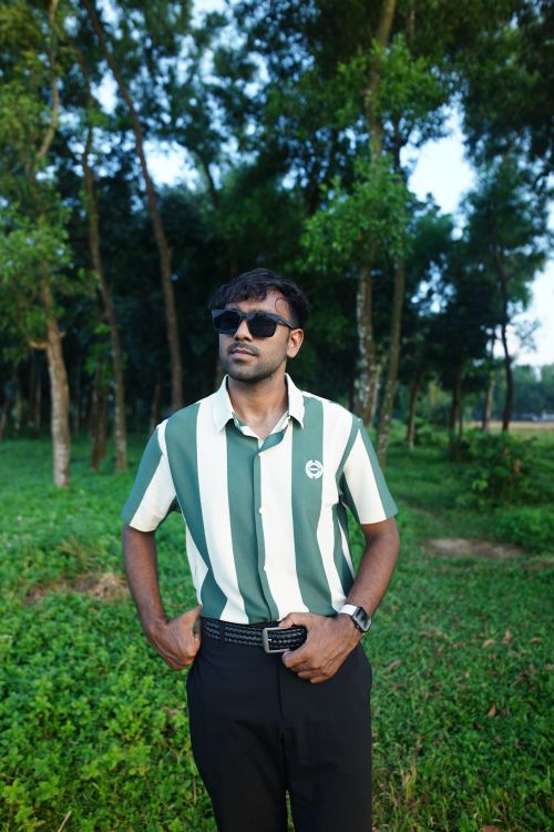 Free Stylish man in striped shirt posing confidently in a lush green forest. Stock Photo