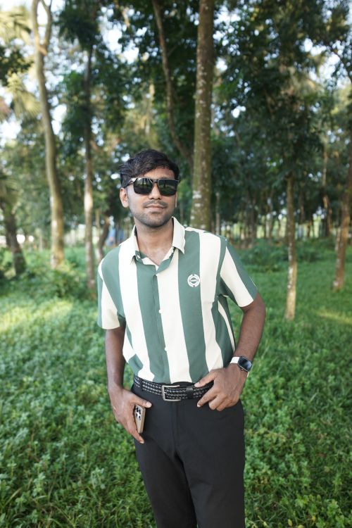 Free Man in stylish attire posing confidently in a lush green forest. Stock Photo