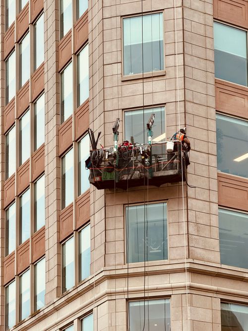 Free Window cleaners working on suspended platform against a Boston skyscraper. Safety equipment visible. Stock Photo