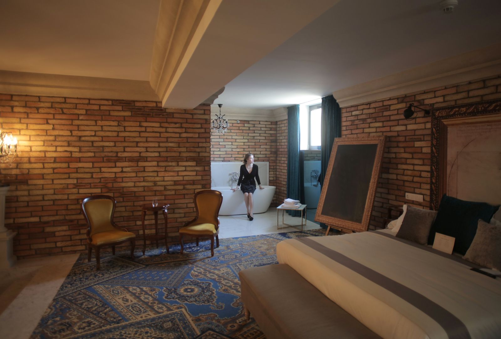 An elegant luxury hotel room with a freestanding bathtub and soft lighting