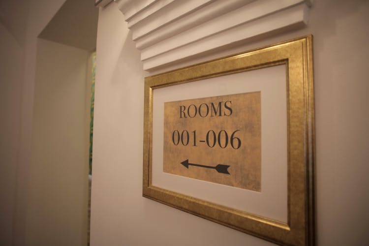 Sign With Rooms Numbers Hanging On White Wall In Modern Hotel