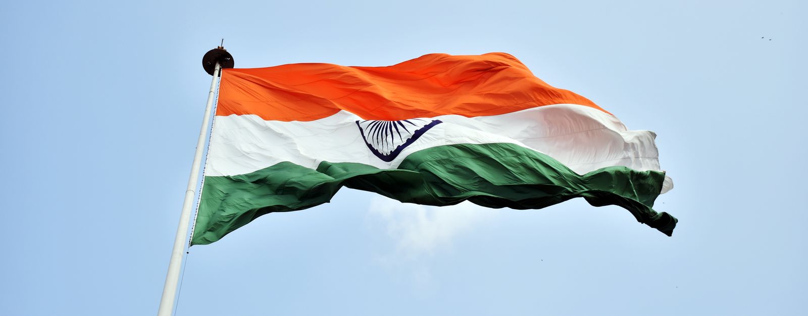 The Indian national flag waves proudly against a clear blue sky in New Delhi.