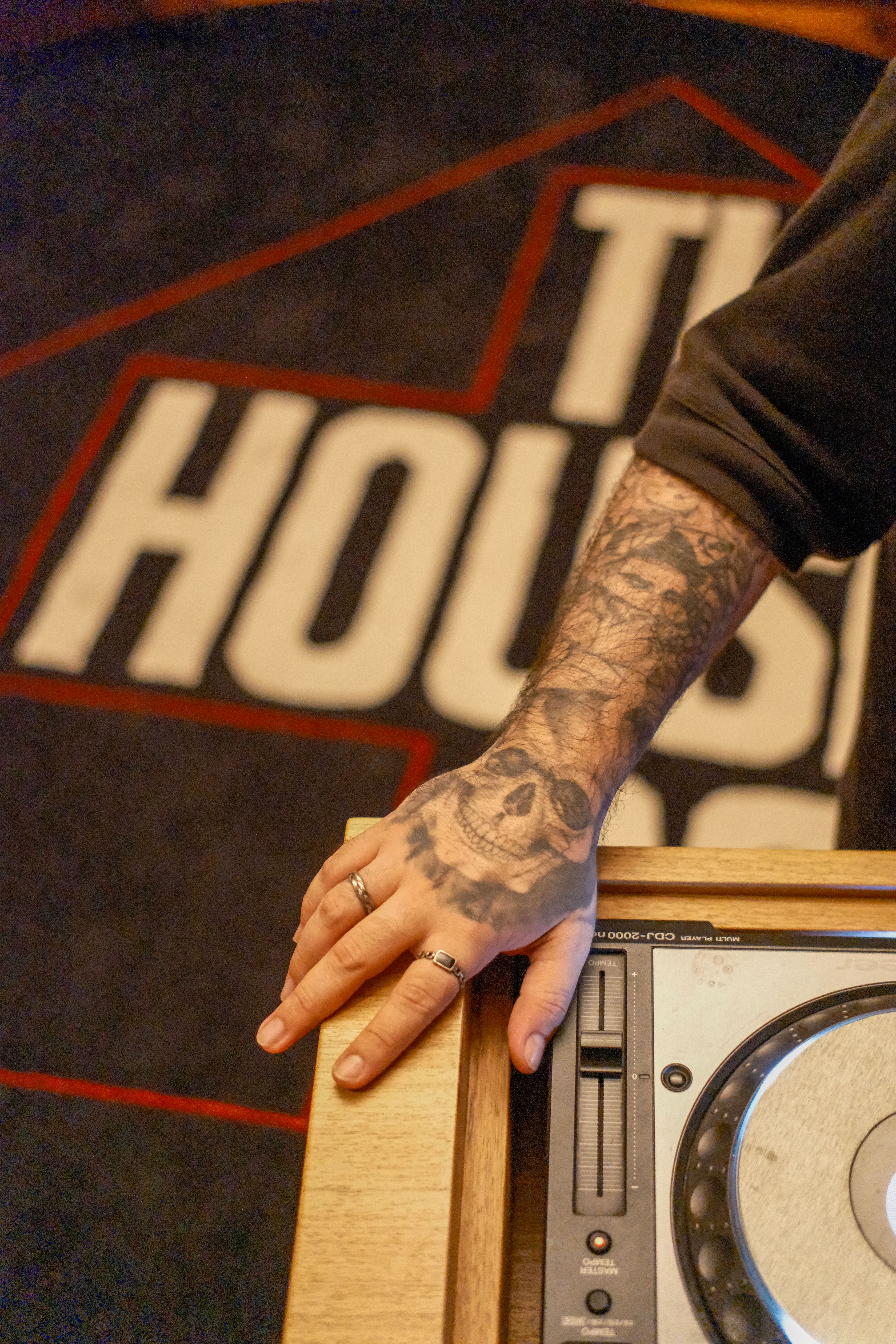 Tattooed hand rests on DJ turntable at an indoor venue in Rio de Janeiro, Brazil.