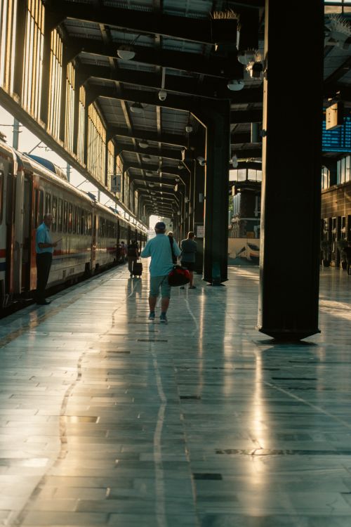Free Passengers walk along the platform in Ankara's station as golden hour sunlight illuminates the scene. Stock Photo