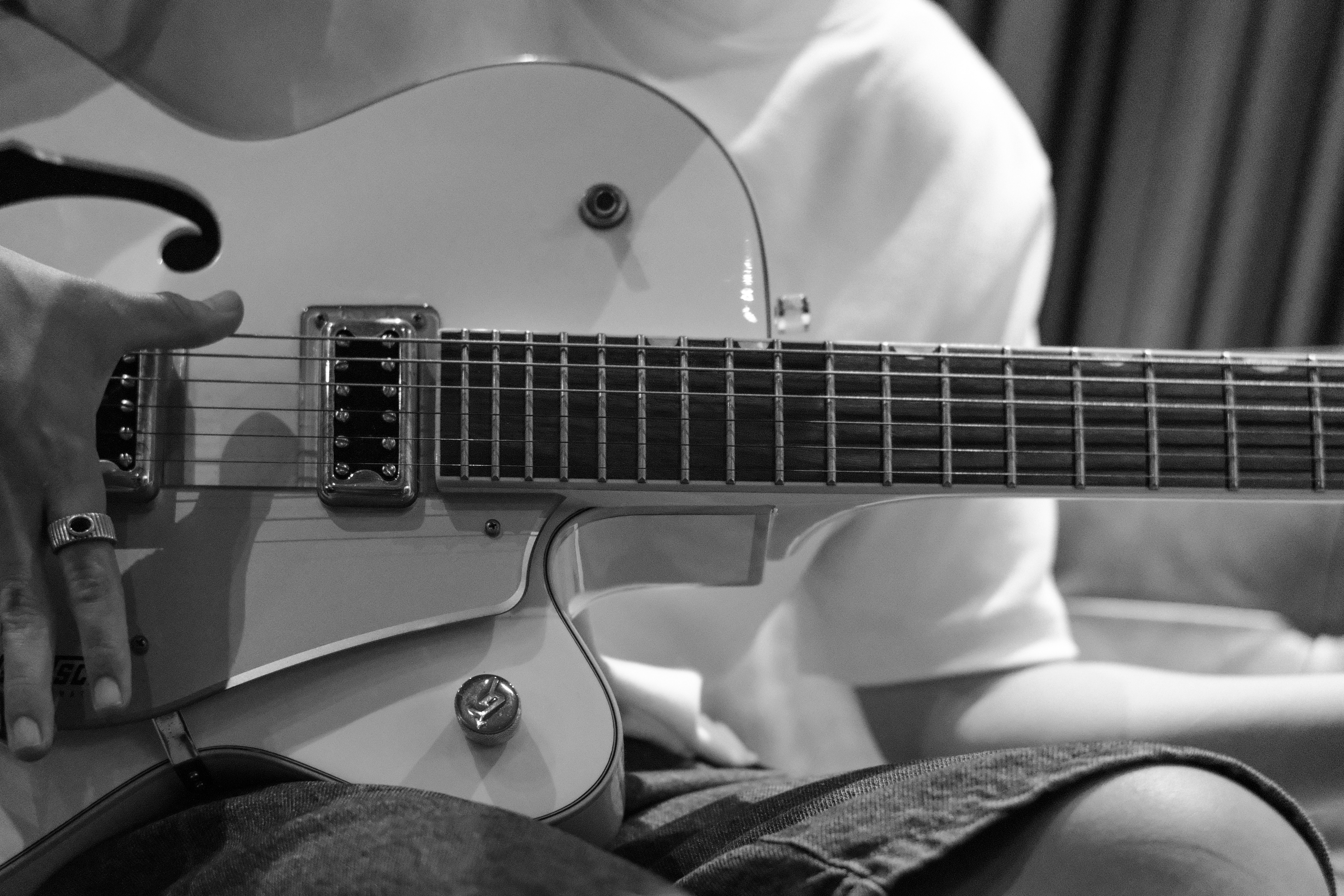 Monochrome image of person playing an electric guitar indoors.