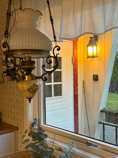 Free Antique chandelier inside a cozy room with a rainy view and outdoor lantern lighting. Stock Photo
