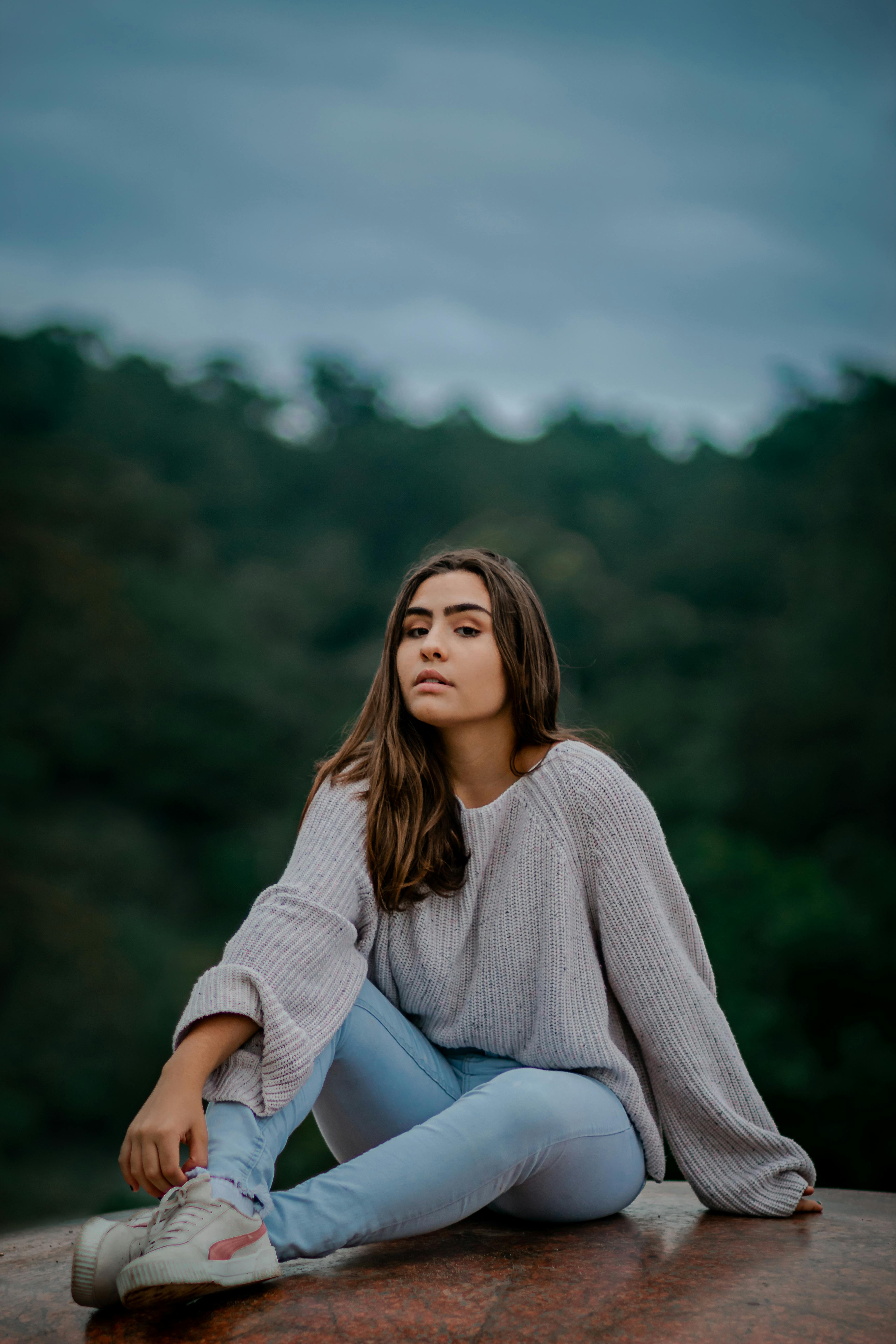 一位穿着休闲装的年轻女子坐在户外，感受着大自然的宁静