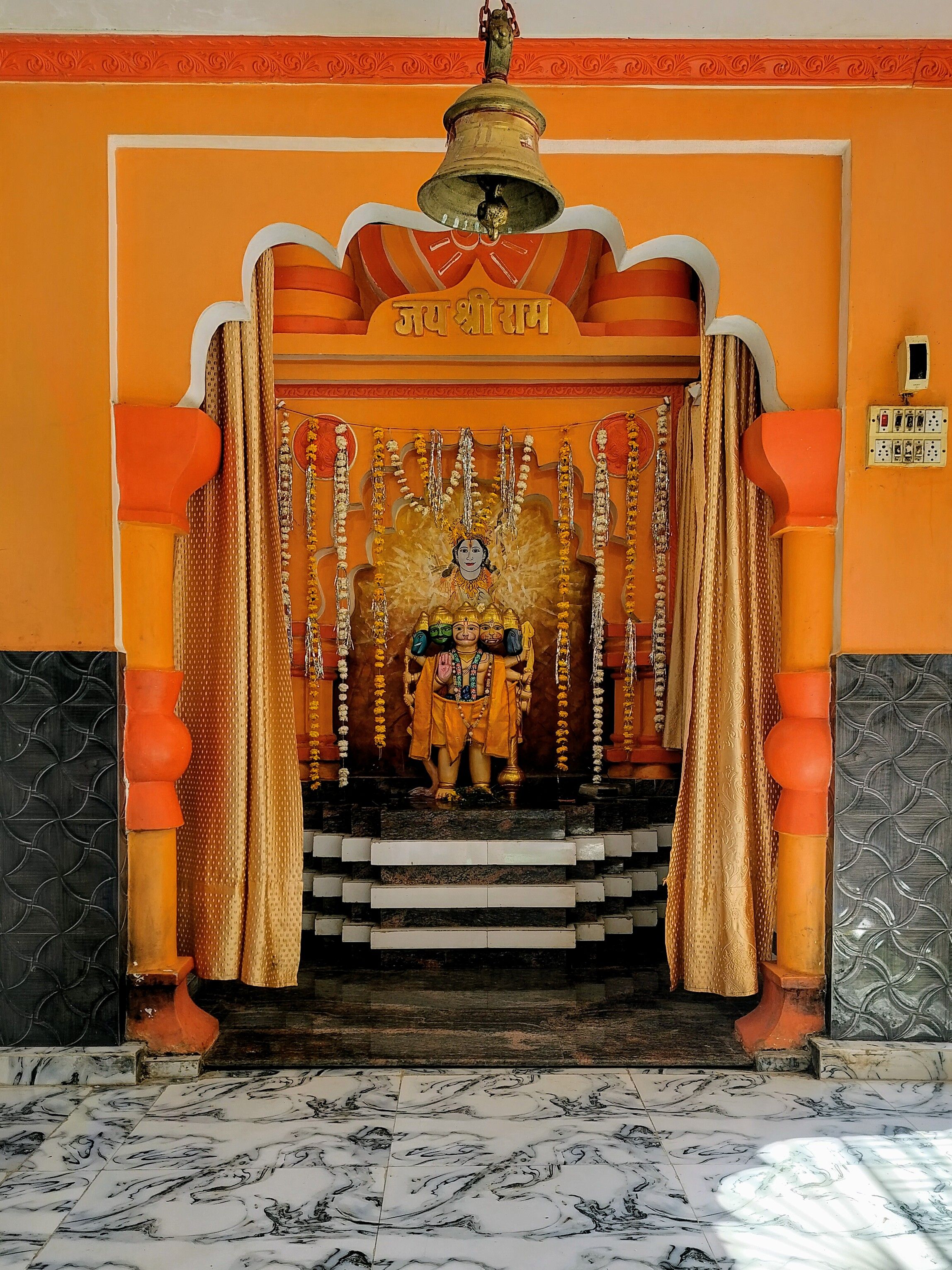 Vibrant Hindu temple altar featuring a deity statue and floral decorations in a traditional Indian setting.