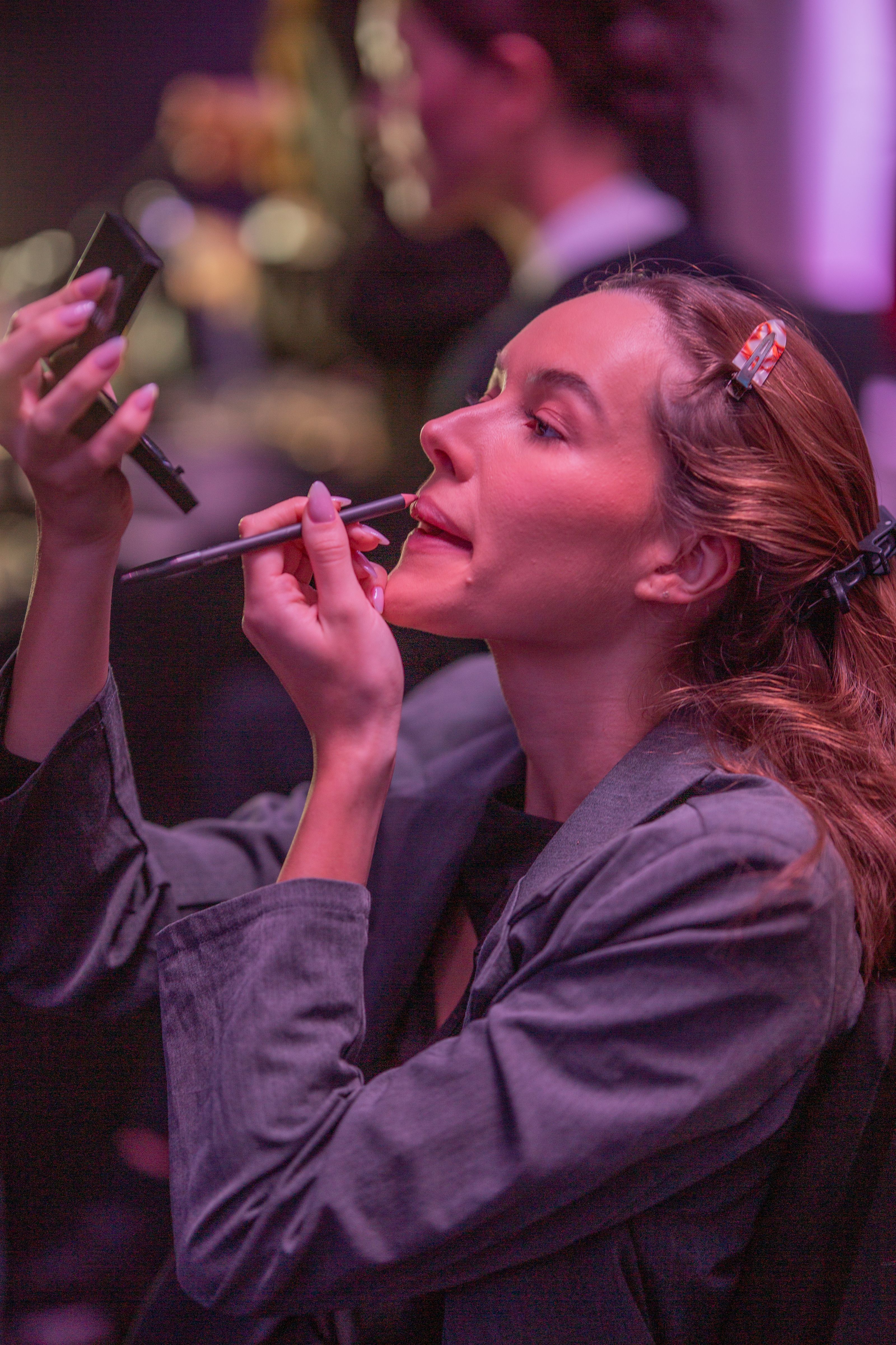 Uma maquiadora aplica batom nos bastidores durante um desfile de moda em Dubai.
