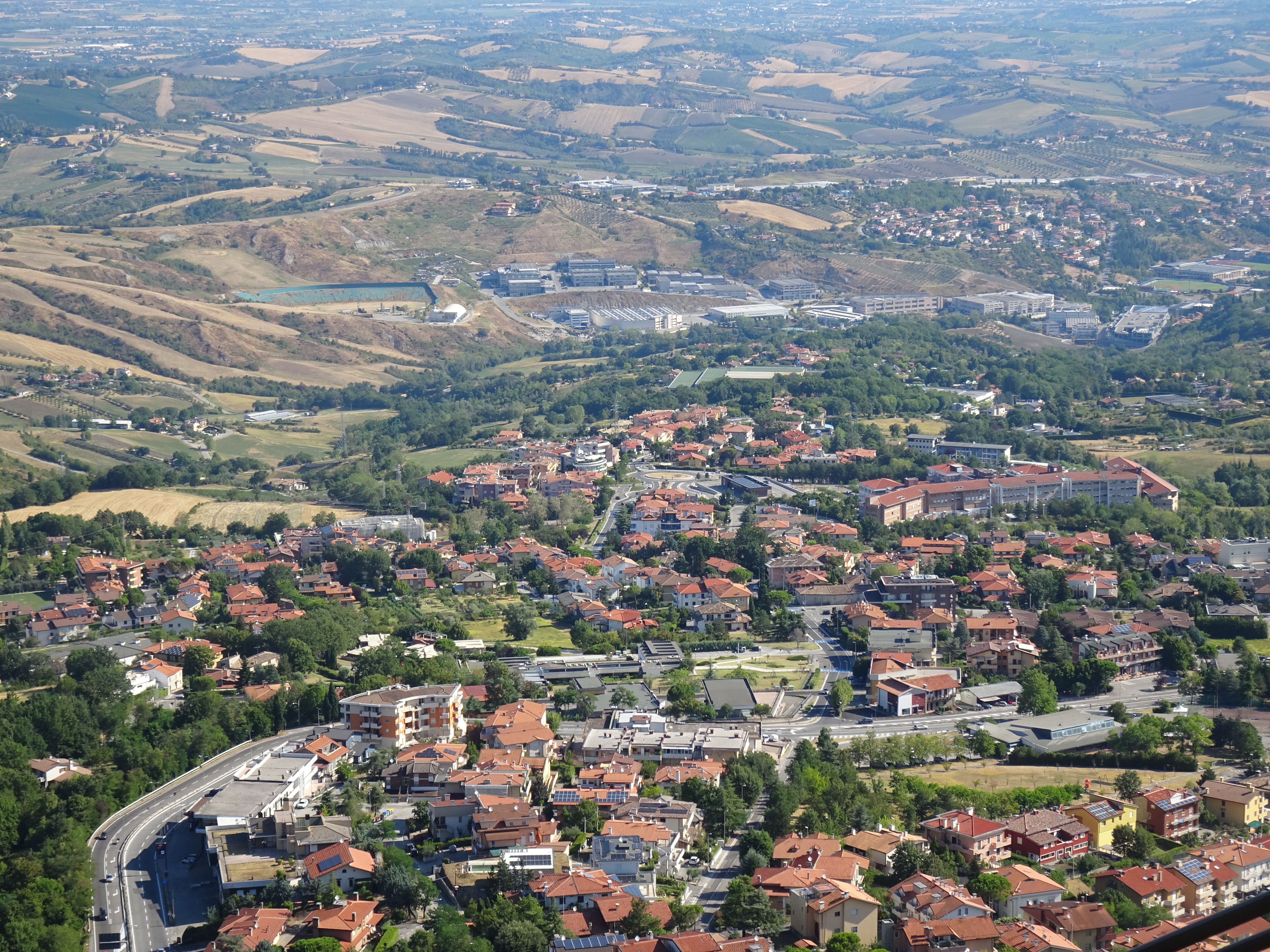 Aerial shot of San Marino's scenic town and countryside on a sunny day.
