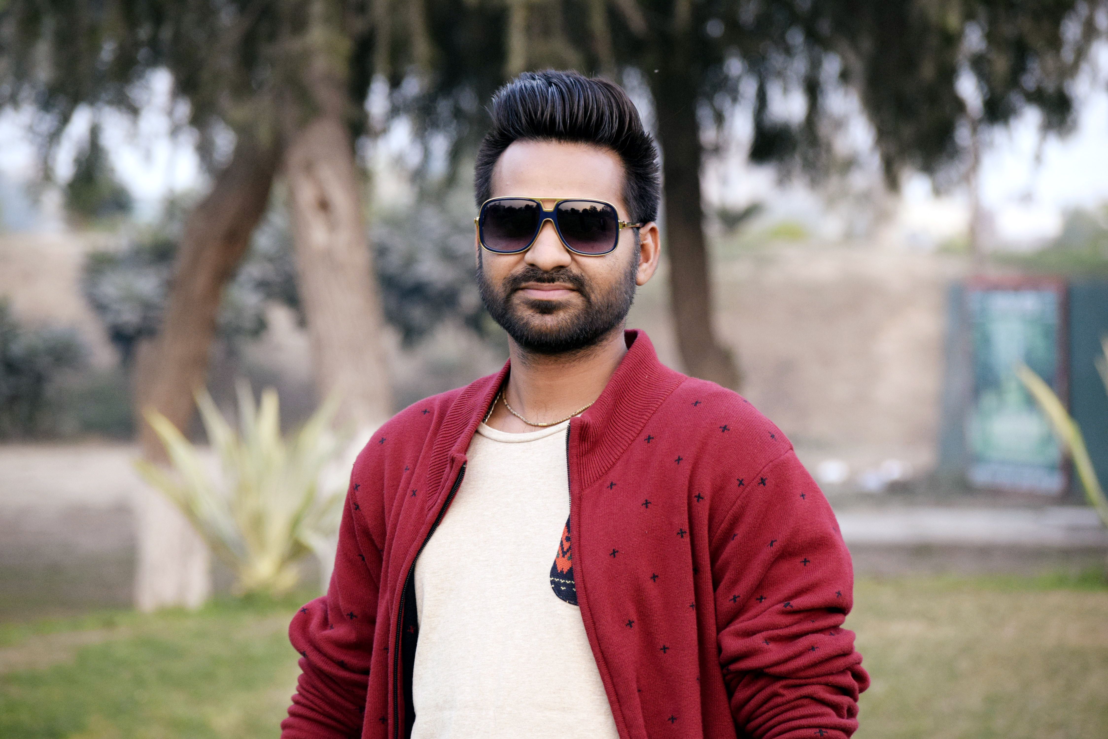 Portrait of a stylish man wearing sunglasses and a red jacket in a park in Bathinda, Punjab.