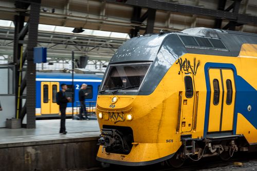 Free Yellow and blue train arrives at a European station with passengers on the platform. Stock Photo