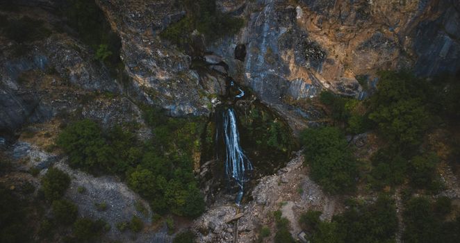 Majestic aerial shot of a waterfall amidst rocky cliffs and lush greenery in Kayseri, Türkiye.
