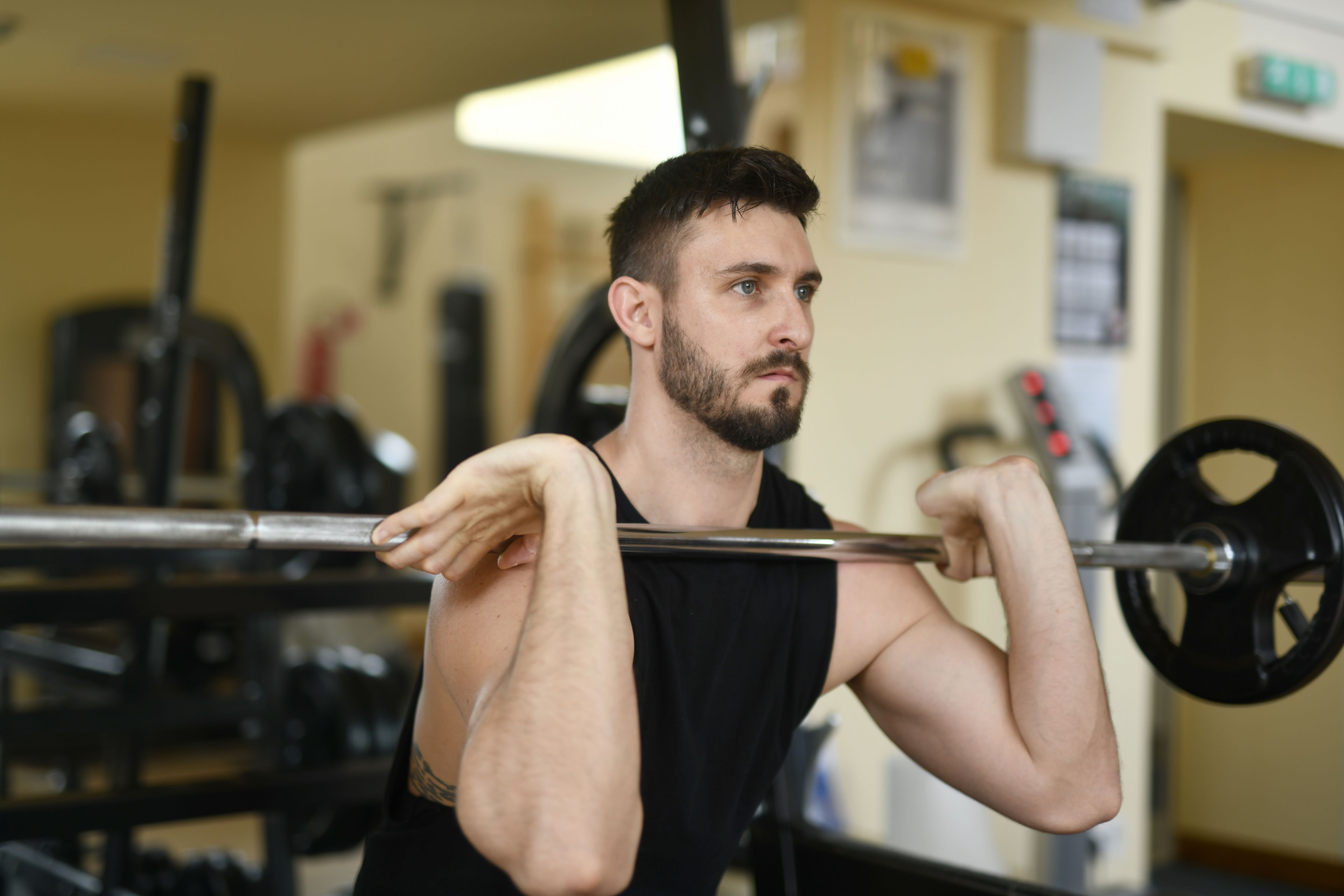 A determined man lifting a barbell in a gym, focusing on strength and fitness.