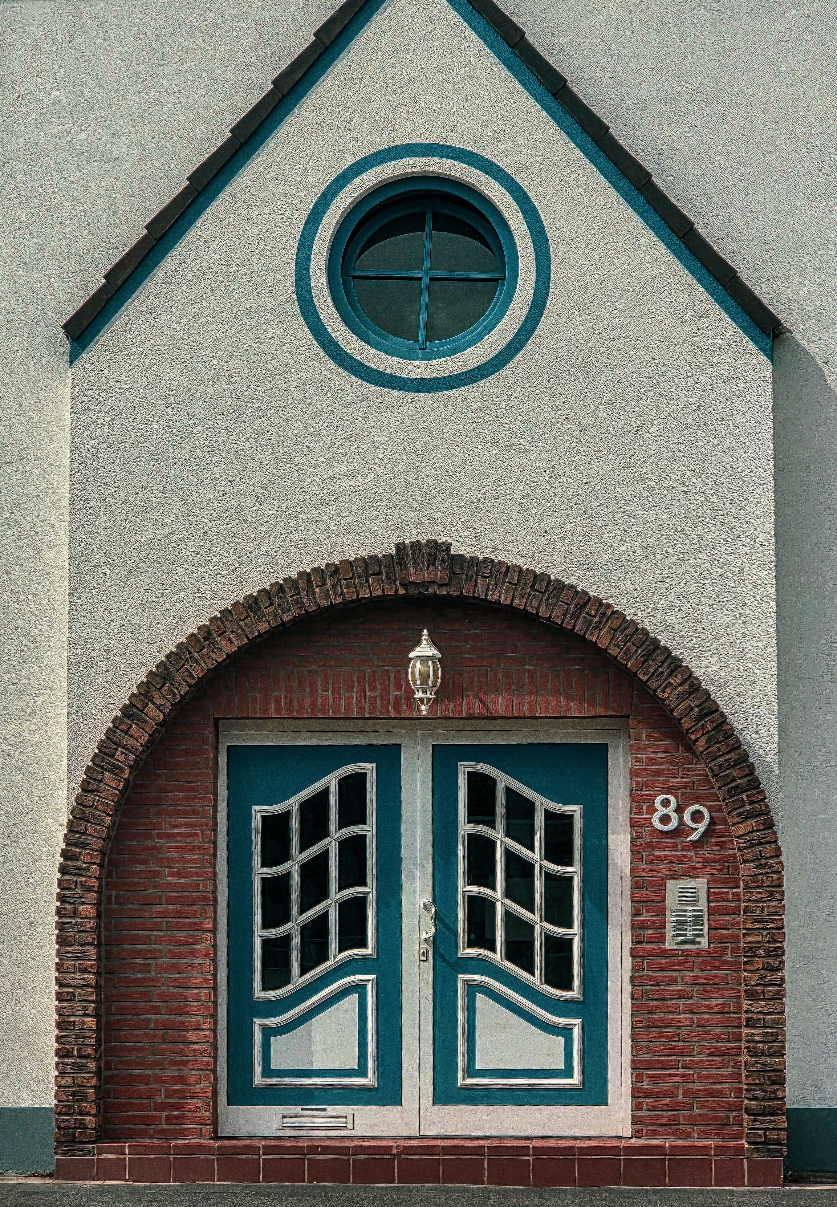 Elegant blue arched double door in a brick facade with vintage design elements.