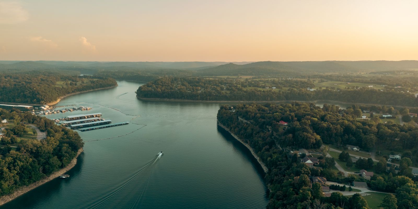 Aerial view of a wide river surrounded by lush forest at sunset