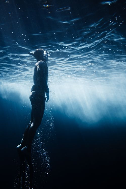 Free A mesmerizing shot of a freediver ascending towards the sunlit surface of the water, captured underwater. Stock Photo