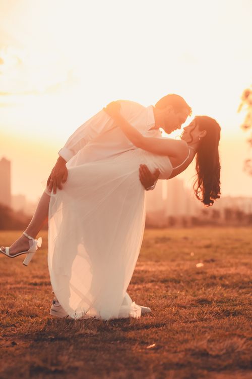 Free A couple romantically embracing during a sunset in an open field. Stock Photo
