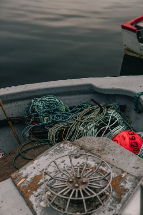 Free View of a fishing boat deck with tangled ropes and a red buoy displaying weathered marine equipment. Stock Photo