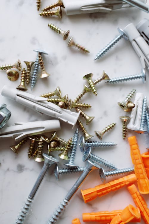 Free Bunch of various multicolored plastic dowels and metal screws placed on white marble table in modern workshop Stock Photo