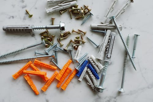 Bunch of various multicolored plastic dowels with metal screws placed on table