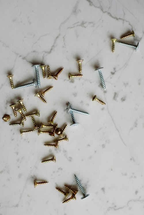 Bunch of various metal screws placed on white marble surface
