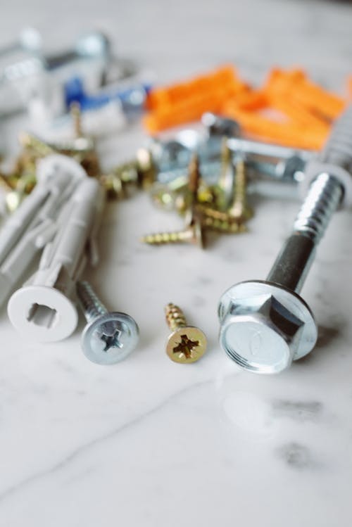 Bunch of various metal screws with multicolored dowels placed on table