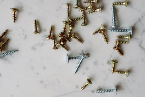 Bunch of various metal screws placed on white table
