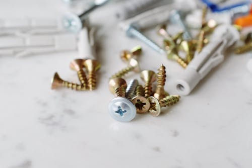 Bunch of various metal screws with plastic dowels placed on white table