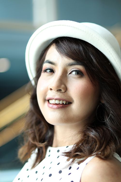 Free Smiling woman in a white hat posing indoors with a bright cheerful expression in Jakarta. Stock Photo