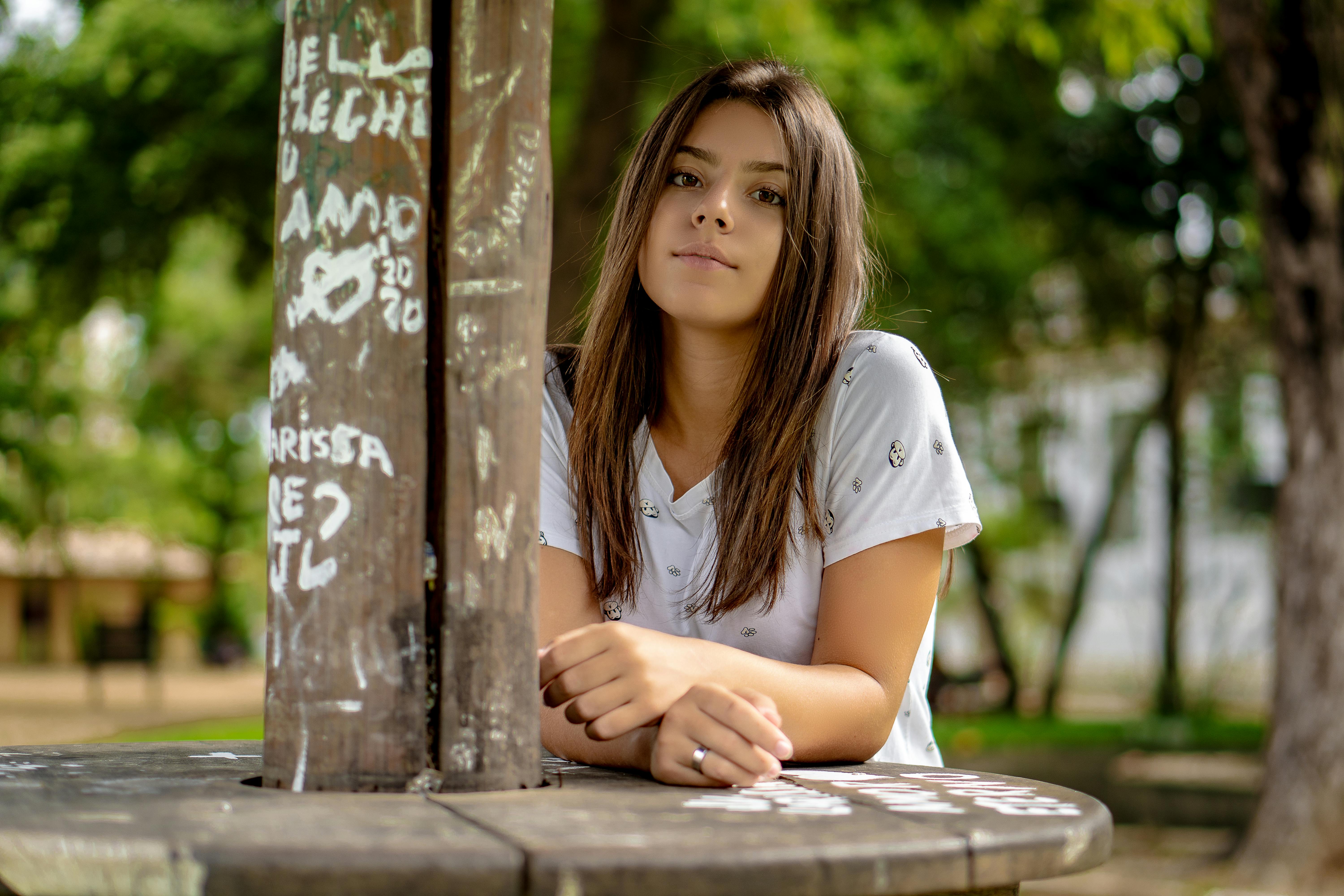 woman in white shirt leaning on brown wooden table