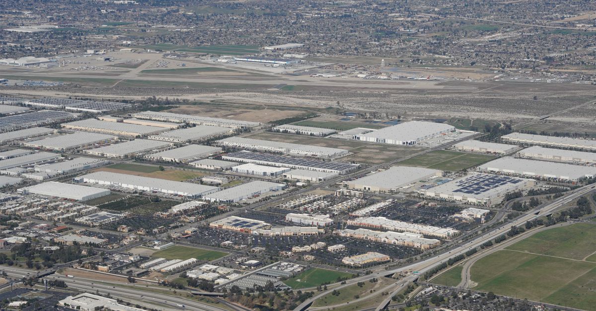 Expansive aerial shot of industrial area near a major airport and urban landscape.