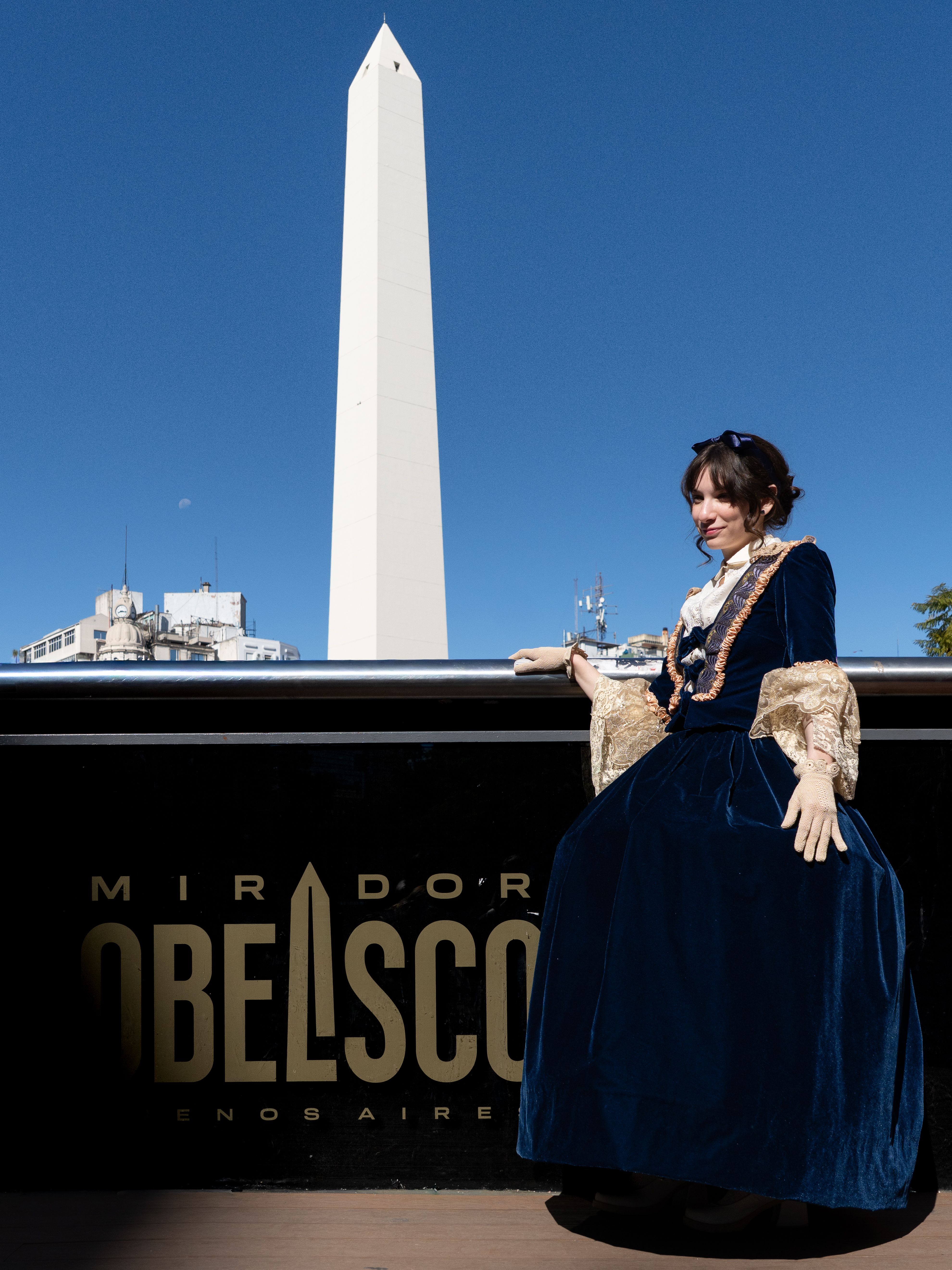 A woman in historical attire poses at the Obelisk landmark in Buenos Aires, Argentina.