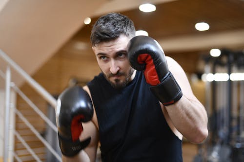 Man In Black Crew Neck Shirt Wearing Black And Red Boxing Gloves