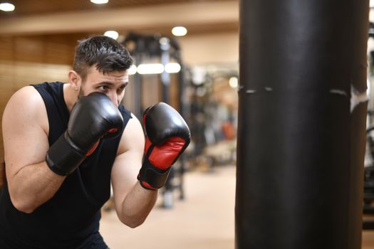 A determined boxer practicing punches on a punching bag indoors.